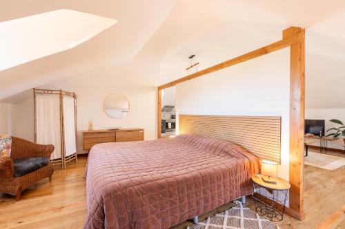 a bedroom with a large bed and a chair at Casa das Eiras, Nº48 in Santana