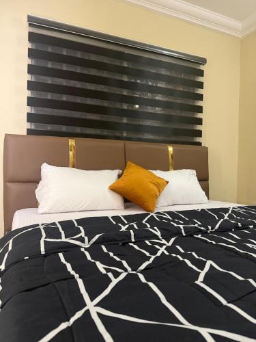 a bedroom with a bed with two pillows and a window at Max Heron in Ikeja