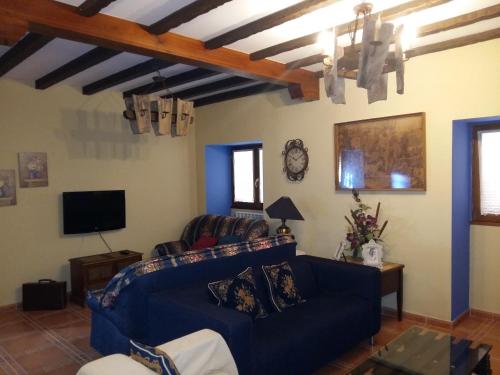 uma sala de estar com um sofá azul e uma televisão em Casa Júnez em Romanillos de Medinaceli