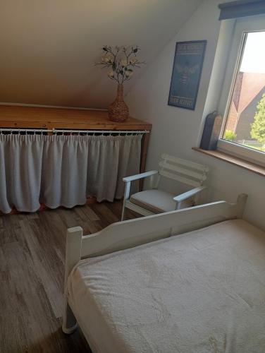 a bedroom with a bed and a chair and a window at Dom Leśny in Wachów