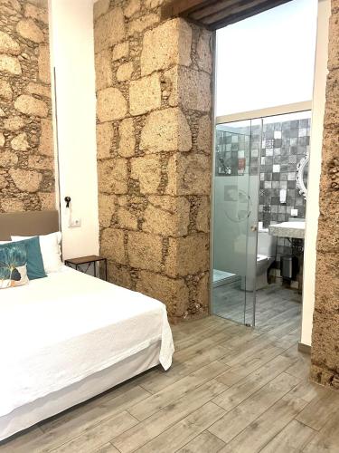 a bedroom with a bed and a stone wall at Hotel The Cathedral Vegueta in Las Palmas de Gran Canaria