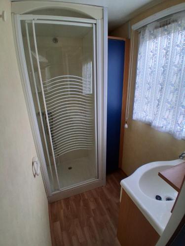 a bathroom with a shower and a sink at Camping du Mesnil - Gaia Vacances in Saint-Aubin-sur-Mer