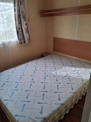 a bedroom with a large bed with a blue comforter at Camping du Mesnil - Gaia Vacances in Saint-Aubin-sur-Mer