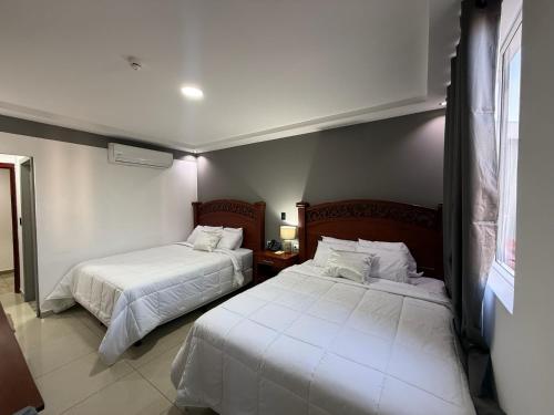 a bedroom with two beds with white sheets at Hotel Rubinos in San Salvador