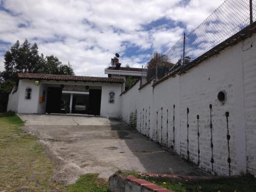 a white building with a gate and a fence at Mansion Samzara Hosteleria in Sangolquí