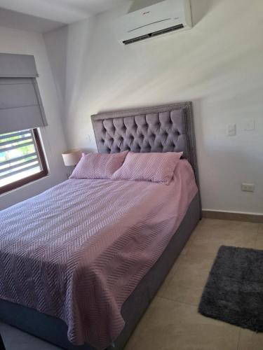a bedroom with a large bed with pink sheets and a window at Departamento en Mazatlán in Mazatlán