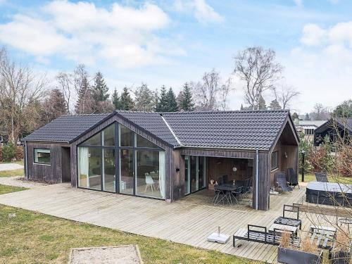 a large house with a wooden deck with glass doors at 8 person holiday home in Væggerløse in Bøtø By