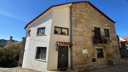 a small stone building with a door and windows at Cominhos & Quartilhos in Sortelha