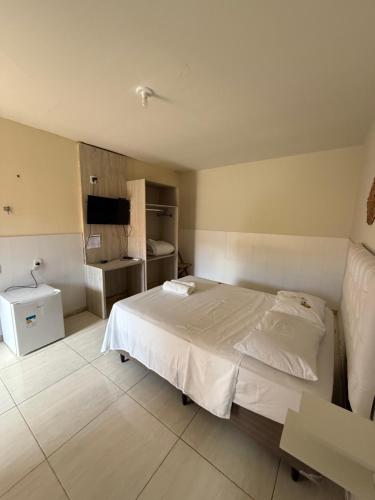 a bedroom with a white bed and a television at Hotel pousada Xique Xique in Piranhas