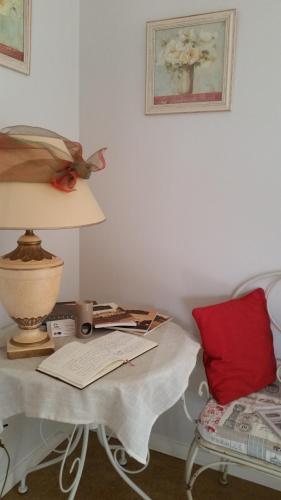 a table with a lamp and a red pillow next to a bed at La Ferme du bois Paris in Ermenonville-la-Petite