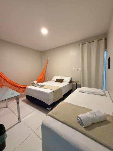 a bedroom with two beds and an orange hammock in it at Pousada Vasconcelos Tianguá in Tianguá