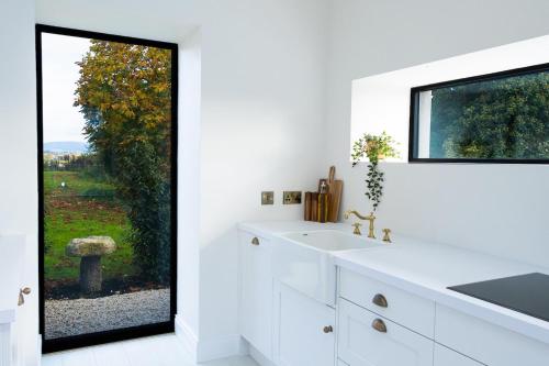 a white bathroom with a sink and a window at Lil's Cottage, Grangecon in Grange Con