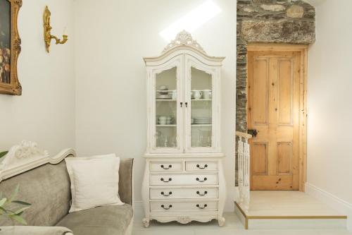 a white cabinet next to a couch next to a door at Lil's Cottage, Grangecon in Grange Con