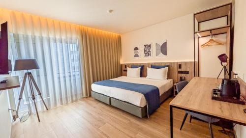 a hotel room with a bed and a desk at Hotel Infante Santo - Lisboa in Lisbon