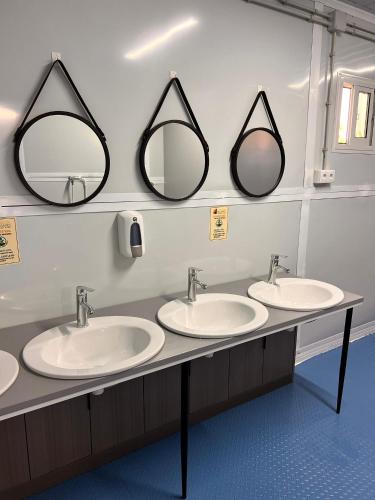 a bathroom with three sinks and two mirrors at Lomas de Balsares in Elche