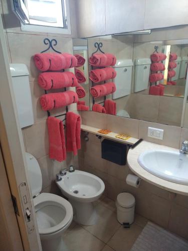 a bathroom with a toilet and a sink and red towels at Cabañas ANANDA KANAN in Villa Giardino