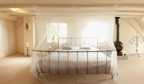 a white bedroom with a bed with a canopy at Patricius House in Oostwoud