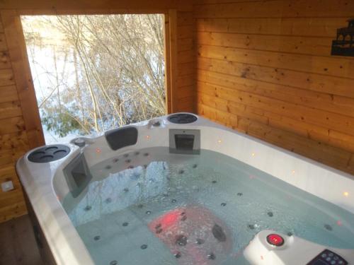 a jacuzzi tub in a room with a window at Chalet flottant sur lac et spa in Mios