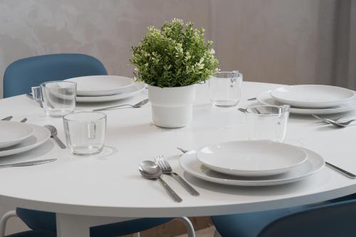 a white table with plates and a potted plant on it at Suites Nador in Nador