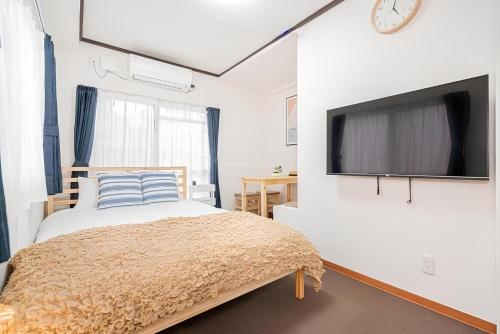 a bedroom with a bed and a tv on a wall at UENO station 7min on foot/Cozy Apartment/Convenient location in Tokyo