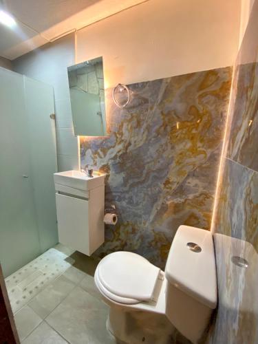 a bathroom with a toilet and a sink and a mirror at Hotel Grand ilama in Cali