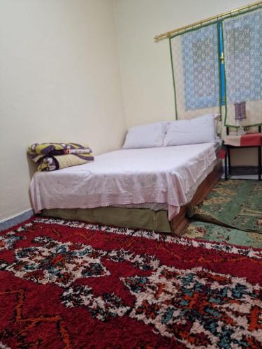 a bedroom with a bed and a rug on the floor at Gite Boutferda in Bou Tferda