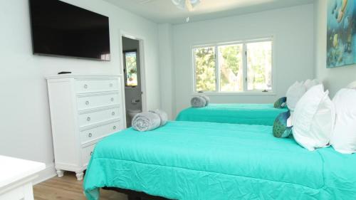 two blue beds in a white bedroom with a tv at 8 Bedrooms With A Pool - 404 Fourth Avenue in West Cape May
