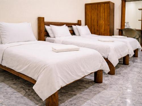 a group of three beds with white blankets on them at The Sandscape Fuvahmulah in Fuvahmulah
