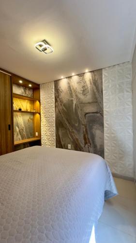 a bedroom with a white bed and a painting on the wall at Loft Completo Compact in Palmas