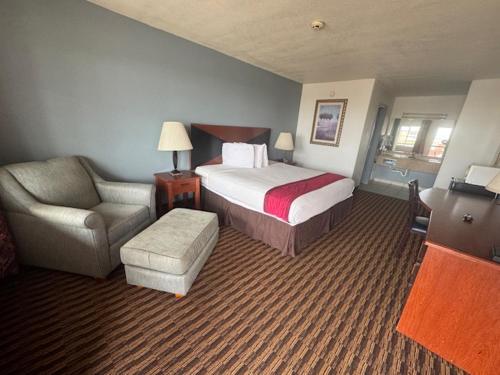 a hotel room with a bed and a chair at Budget Host Inn in Salina