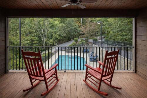 two rocking chairs on a porch with a swimming pool at Forge Chalet- Cozy Stay with Bunks, Views and Hot Tub in Pigeon Forge