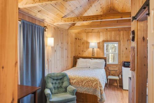 a bedroom with a bed and a chair in a room at Davis Outpost Pet-Friendly Quiet Cabin w AC Screened Sunroom Walk to Trails in Otter Creek