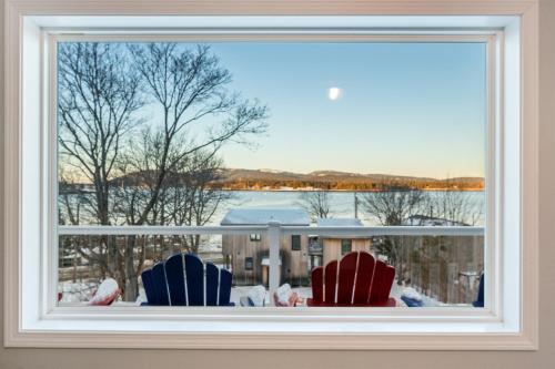 two chairs sitting on a window sill looking out at the water at Phoenix Aerie Birds-Eye Harbor Views, Maritime Loft, Harbor Watch Sunrise Deck in Southwest Harbor