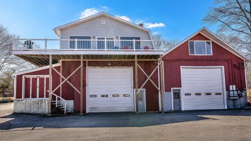 a red barn with two garage doors and a balcony at Phoenix Aerie Birds-Eye Harbor Views, Maritime Loft, Harbor Watch Sunrise Deck in Southwest Harbor