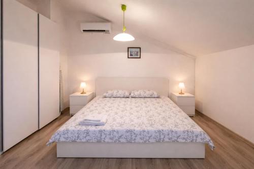 a white bedroom with a bed and two night stands at Apartments Urban Porec in Poreč