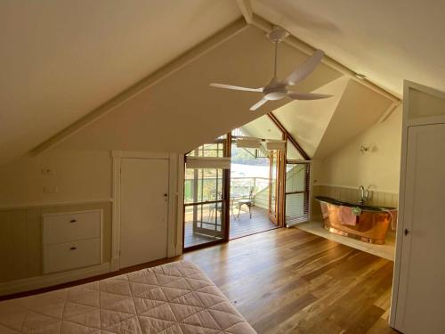an attic room with a ceiling fan and wooden floors at The Haven Cottage Point Sydney in Cowan