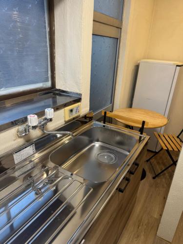 a kitchen with a stainless steel sink and a table at Kurmon Inn in Omachi