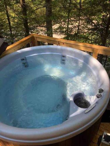 a jacuzzi tub with blue water on a deck at Theodore Tiny Cabin- RRG Hot Tub Pet Friendly in Slade