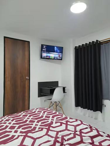 a bedroom with a bed and a television on the wall at Hotel Chemy in Quito