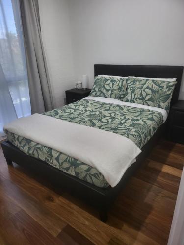 a bed with a green and white blanket and a window at Treasure in Karabah in Queanbeyan