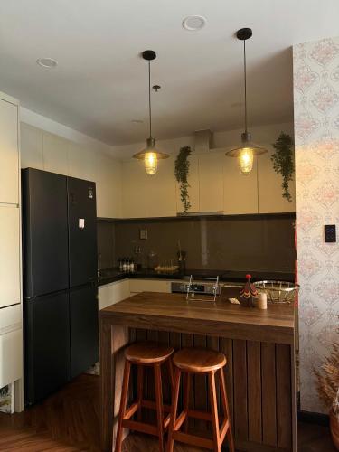 a kitchen with a black refrigerator and two stools at 221B Baker in Ga Phú Văn