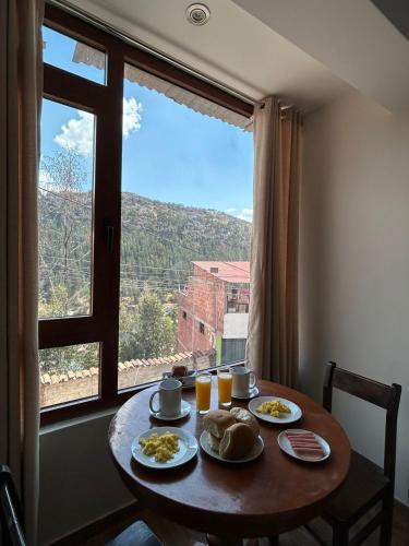 a table with plates of food and a large window at Juan Placido Hospedaje in Cusco