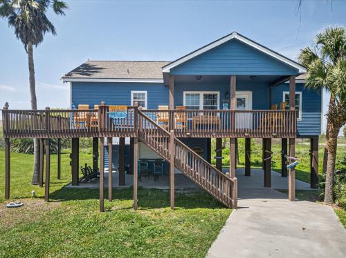 a blue house with a large deck in front of it at Caribbean Palm Retreat 3BR Near Crystal Beach Fireplace in Bolivar Peninsula