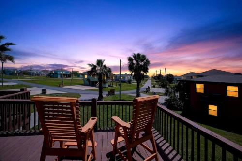 two chairs sitting on a balcony with a sunset at Caribbean Palm Retreat 3BR Near Crystal Beach Fireplace in Bolivar Peninsula