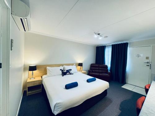 a hotel room with a large bed and a chair at Edinburgh Motor Inn in Warragul