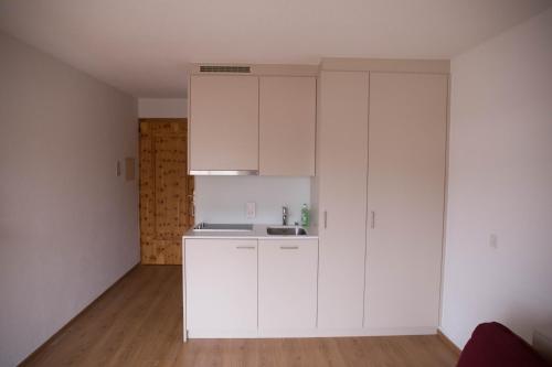 a white kitchen with white cabinets and a wooden floor at Chesa Surlej Apartment in Surlej
