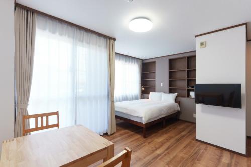 a bedroom with a bed and a table and a television at Kent Clair Ishigaki Bay in Ishigaki Island