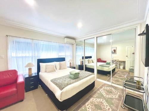 a bedroom with a large bed and a red couch at North Ryde Guesthouse in Sydney