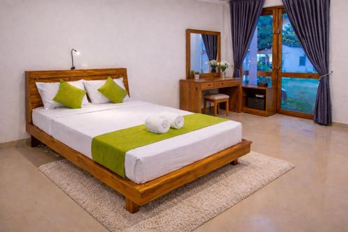 a bedroom with a large bed with a desk and window at yashna villas in Pottuvil