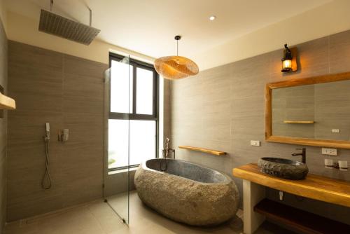 a bathroom with a large stone tub and a mirror at Villa Lotus in Ko Phangan